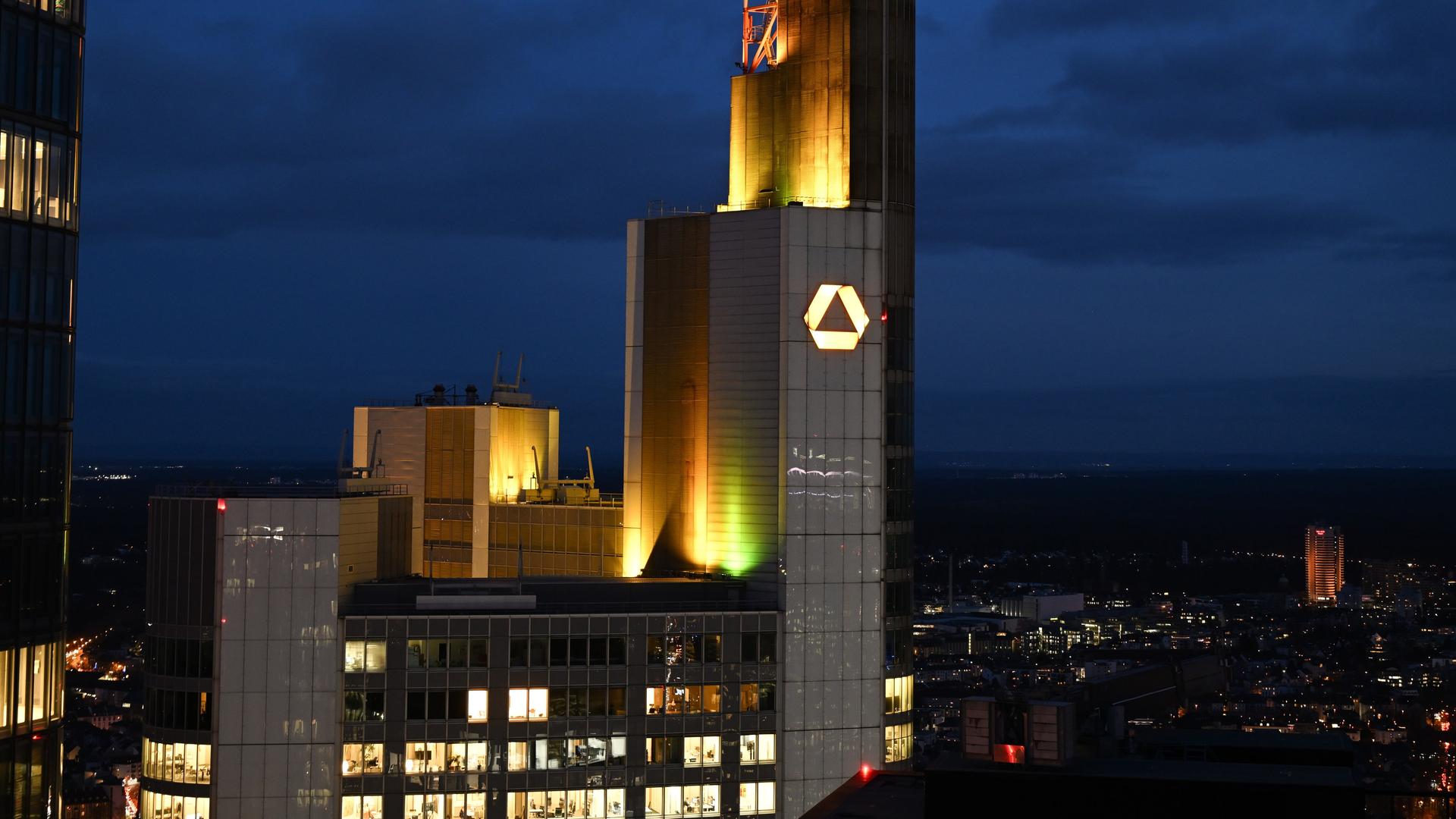 Das Unternehmenslogo leuchtet bei Sonnenuntergang auf der Zentrale der Commerzbank.