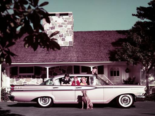 Eine vierköpfige Familie in ihrem Mercury Monterey-Auto auf der Einfahrt ihres Hauses, 1959. Ihr Hund sitzt neben dem Auto.