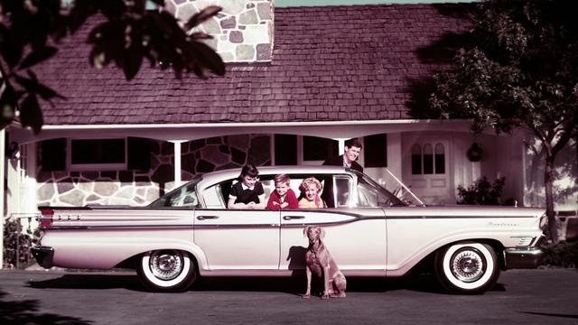 Eine vierköpfige Familie in ihrem Mercury Monterey-Auto auf der Einfahrt ihres Hauses, 1959. Ihr Hund sitzt neben dem Auto.