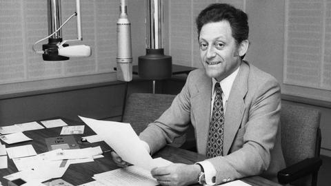 Schwarz-weiß Bild von Hans Rosenthal im Jahr 1970 bei der Moderation seiner Hörfunksendung "Klingendes Sonntagsrätsel" in Berlin in einem Studio vor Mikrofonen.