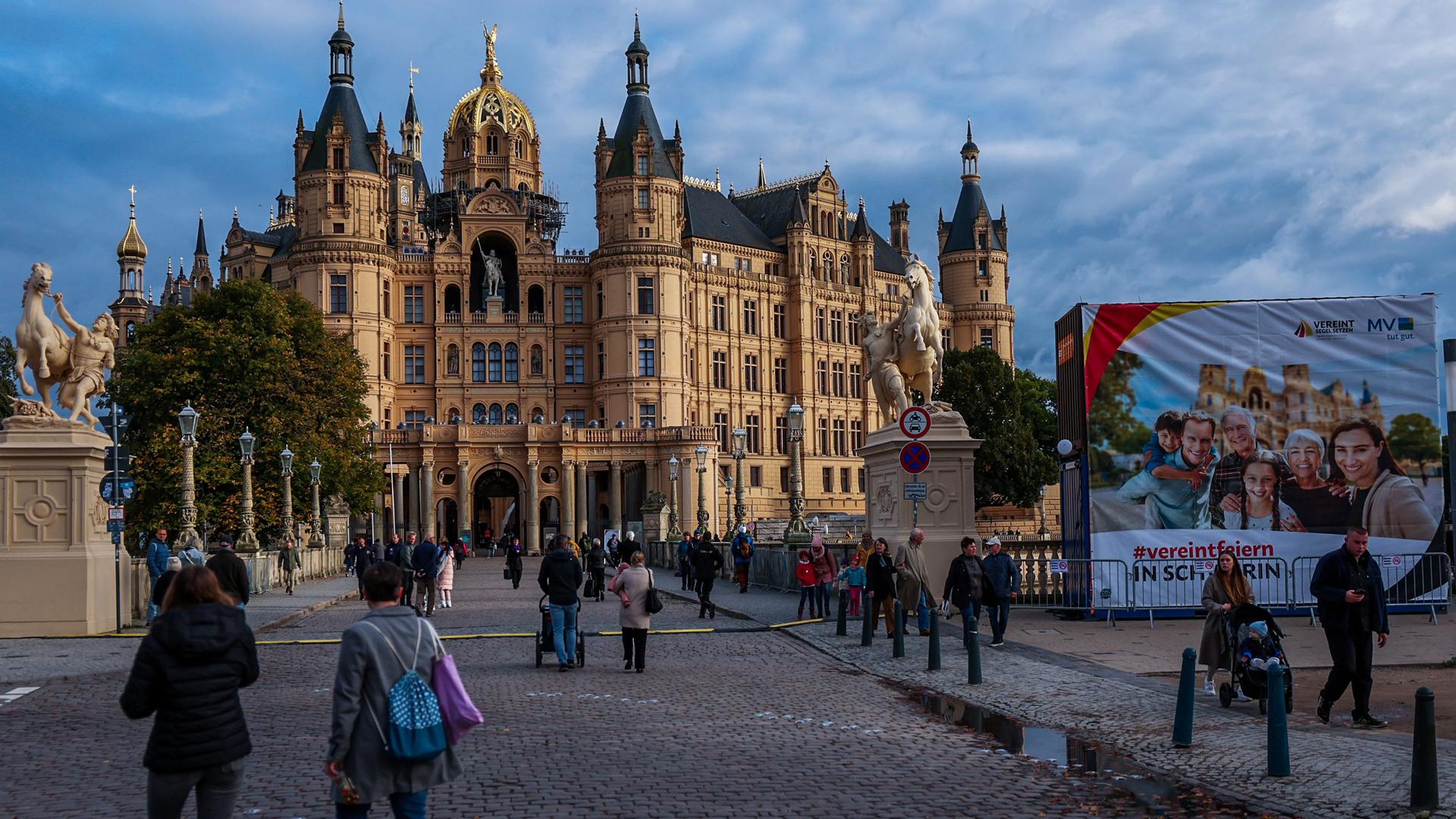 Besucher der Feierlichkeiten zum Tag der Deutschen Einheit stehen vor dem Schweiner Schloss. 