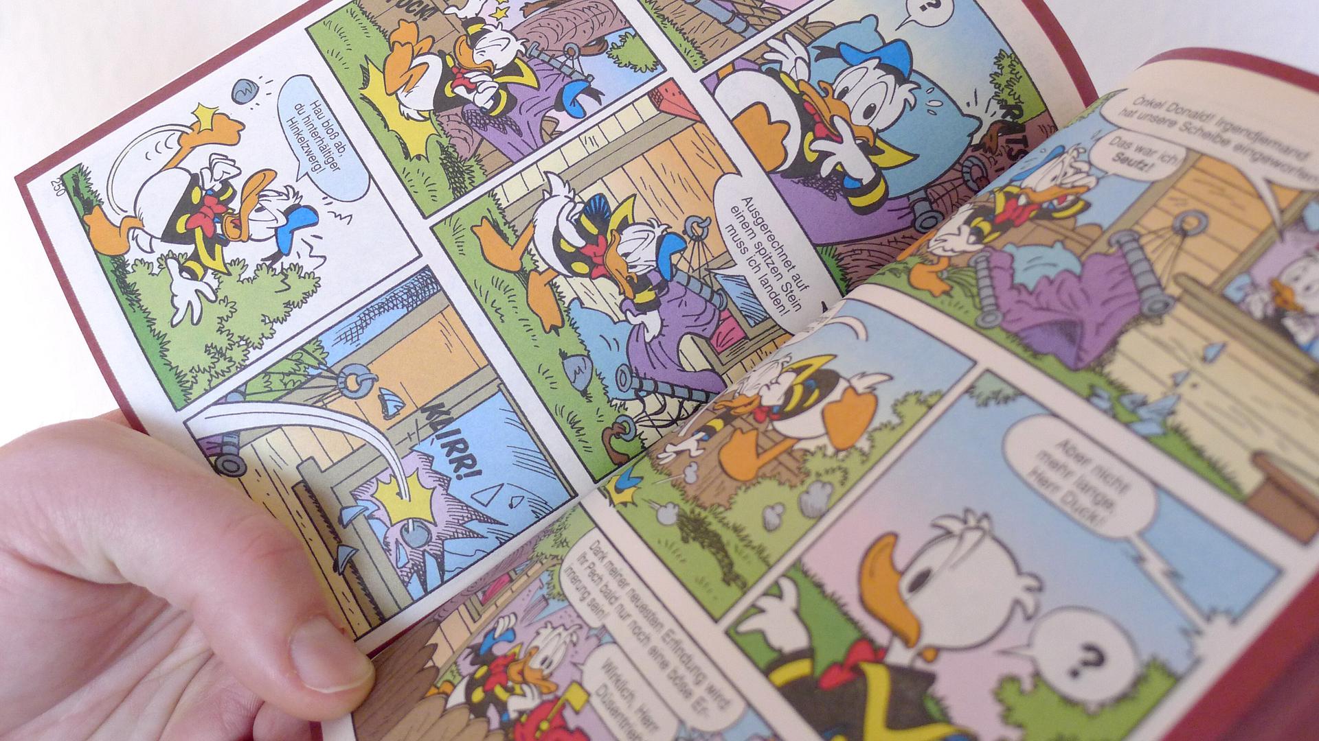 Eine Hand hält ein offenes Donald Duck Heft, ein LTB, "Lustiges Taschenbuch Comic". Eine Hand hält ein offenes Donald Duck Heft, ein LTB, "Lustiges Taschenbuch Comic".