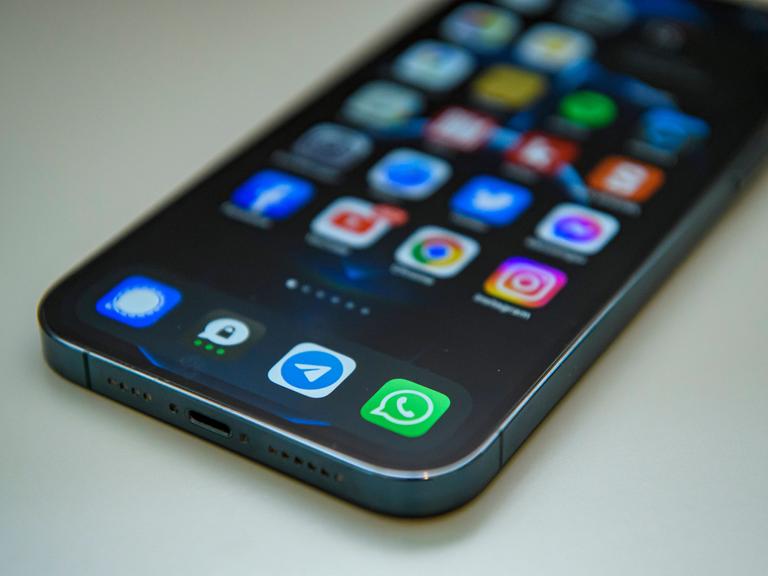 Auf einem Handy sind am unteren Rand des Bildschirms verschiedene Messener-Apps. Darunter ist WhatsApp, Signal, Threema und Telegram.