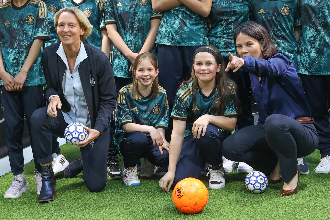 Bundesaußenministerin Annalena Baerbock (rechts) und Martina Voss-Tecklenburg, Frauen-Bundestrainerin, posieren mit jungen Fußballerinnen des SC Siemensstadt beim WM-Kick-Off im Auswärtigen Amt.