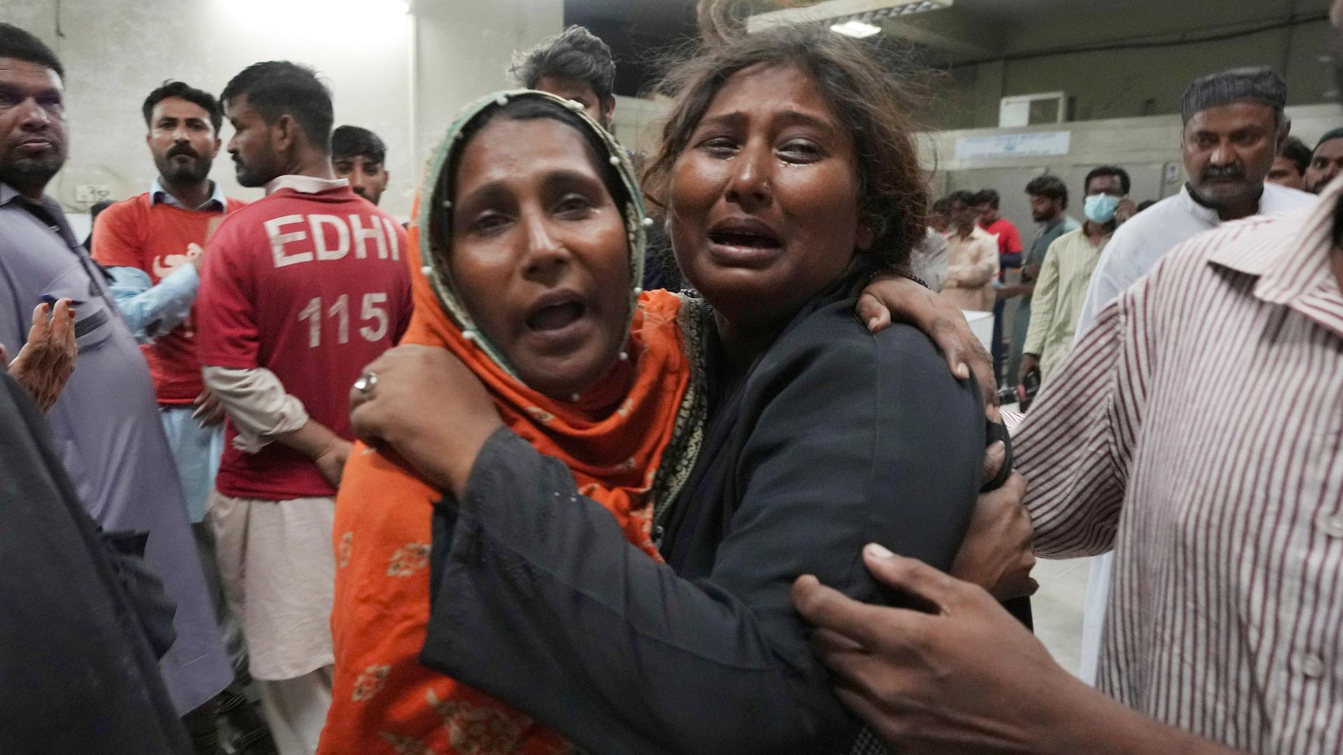 Zwei Frauen in Pakistan umarmen sich tröstend und weinen.