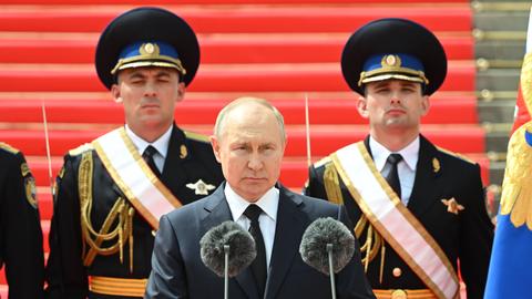 Russlands Präsident Putin bei einer Open-Air-Ansprache. Hinter ihm stehen zwei Männer in Uniform