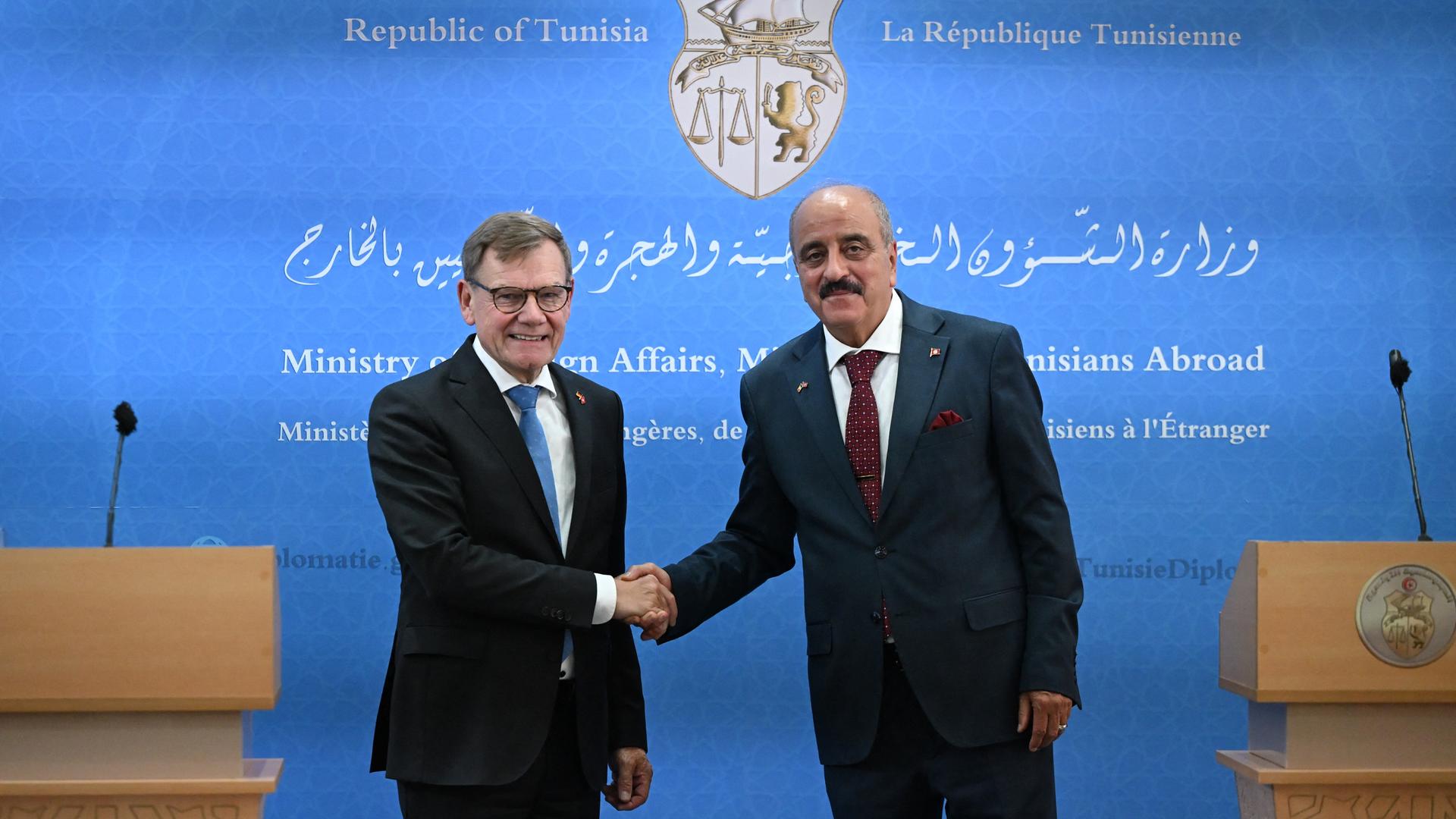 Johann Wadephul (CDU), Bundesaußenminister, gibt mit Mohamed Nafti, Außenminister von Tunesien, eine Pressekonferenz. Beide schütteln sich vor einem blauen Hintergrund die Hände.