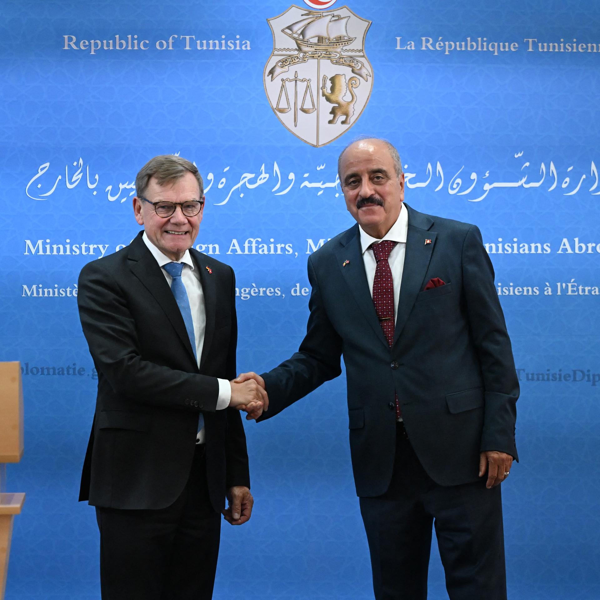 Johann Wadephul (CDU), Bundesaußenminister, gibt mit Mohamed Nafti, Außenminister von Tunesien, eine Pressekonferenz. Beide schütteln sich vor einem blauen Hintergrund die Hände.