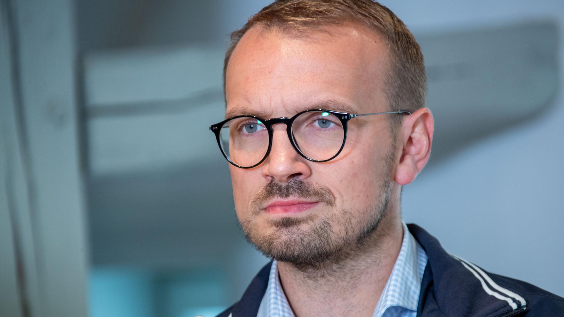 Landrat Stefan Sternberg, kurze blonde Haare, blau-weiß kariertes Hemd, schwarze Brille, schaut links an der Kamera vorbei.