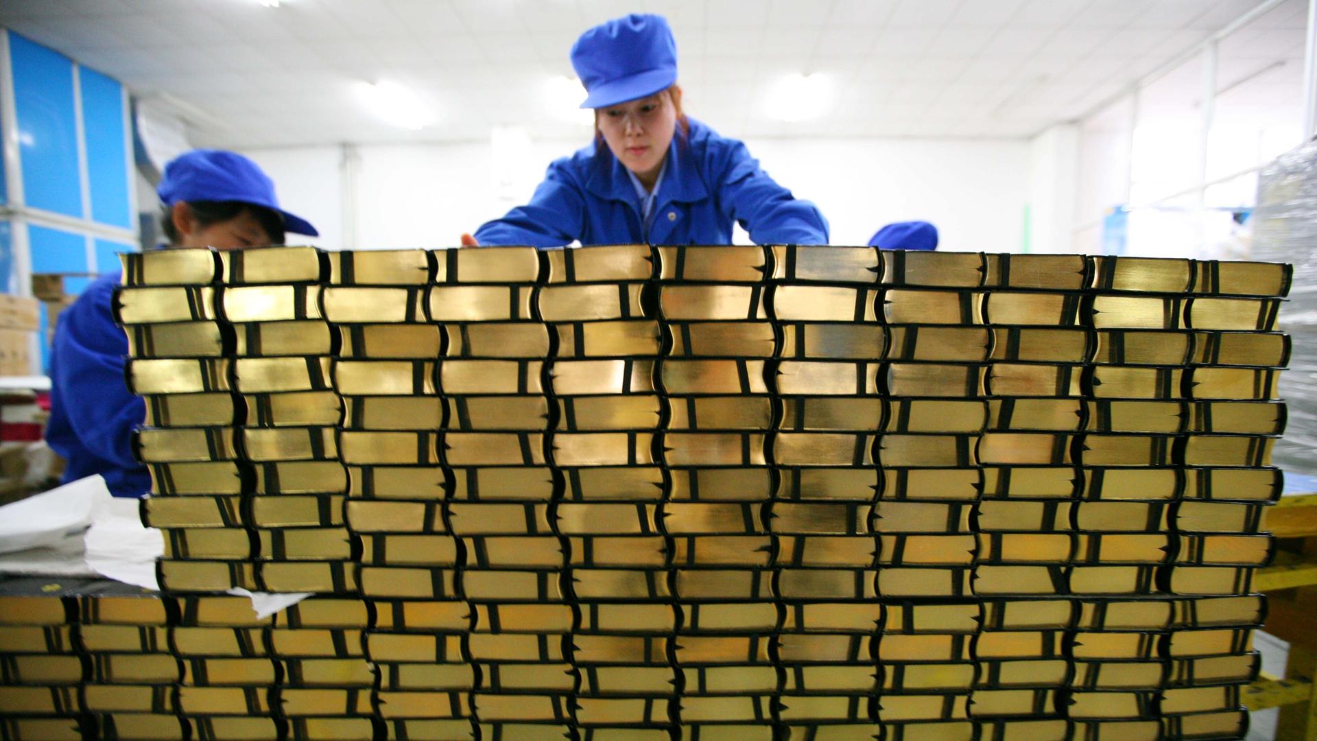 Mitarbeiterinnen der chinesischen Amity-Druckerei hinter einer Wand aus Bibeln. Mitarbeiterinnen der chinesischen Amity-Druckerei hinter einer Wand aus Bibeln.