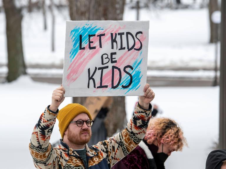 Demonstrant in Minnesota, USA, mit einem Schild "Let Kids be Kids" bei einer Demonstation für die Rechte von Trans-Jugendlichen