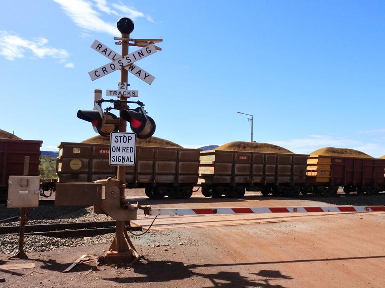 Ein Güterzug mit Waggons für Eisenerz fährt durch Australien.