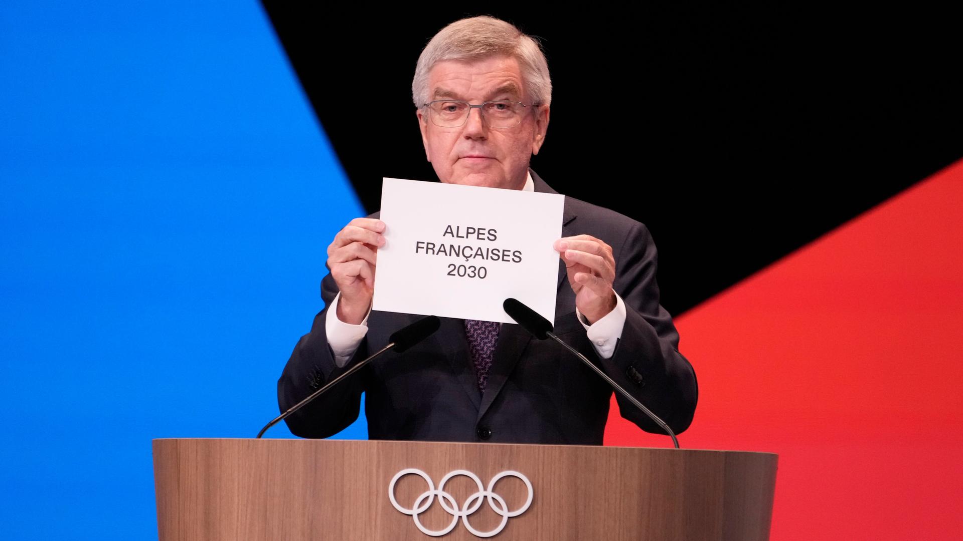 IOC-Präsident Thomas Bach hält einen Zettel hoch.