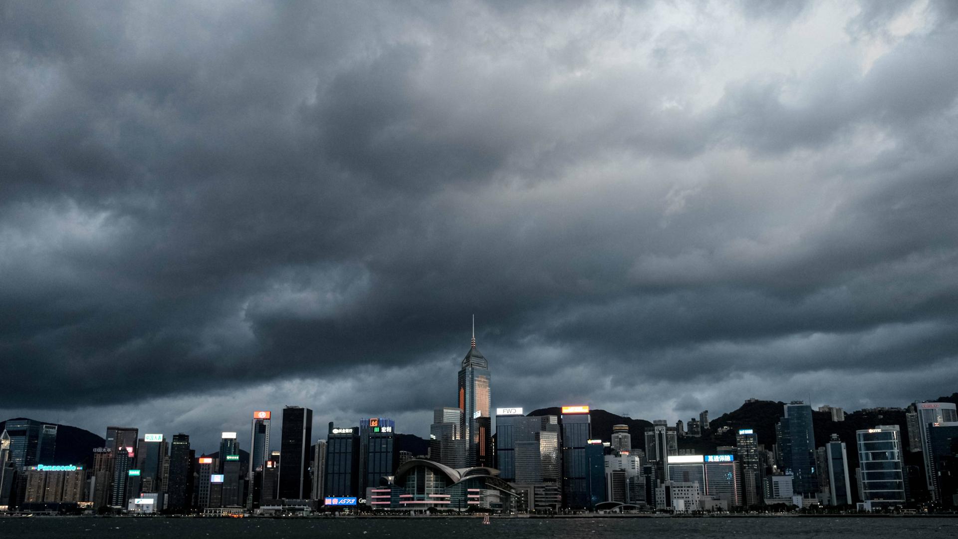 Die Skyline von Hongkong, am Himmel sind tiefe, dunkle Wolken zu sehen. 