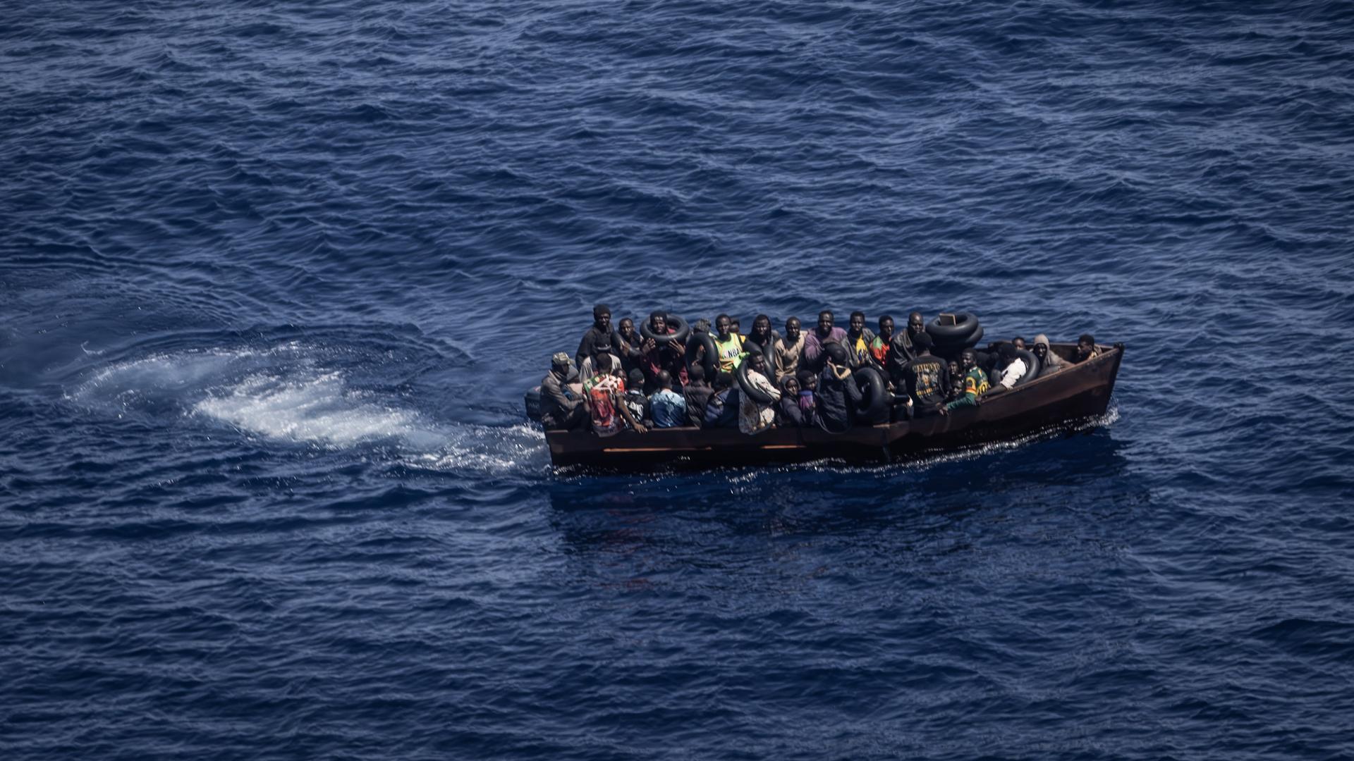 Migranten sitzen dicht gedrängt in einem kleinen Boot.
