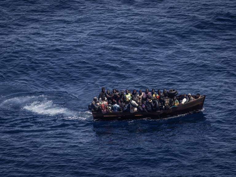 Migranten steuern ein Boot von der Nordküste Afrikas über das Mittelmeer in Richtung der italienischen Insel Lampedusa. Von Tunesien aus setzen immer mehr afrikanische Flüchtlinge nach Italien über. Viele Migranten zahlen für die Reise nicht nur finanziell einen hohen Preis.