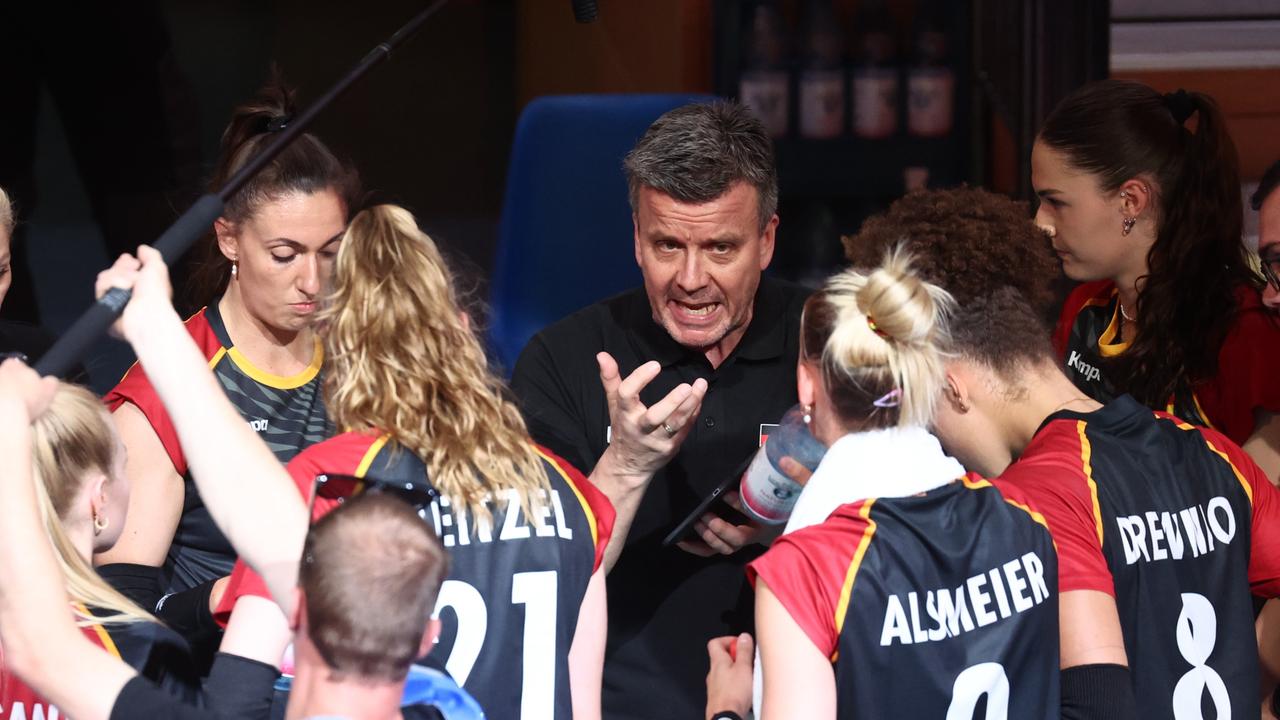 Zu sehen sind Spielerinnen des Frauen-Volleyballnationalteams mit ihrem Trainer Alexander Waibl. Sie sprechen miteinander. 