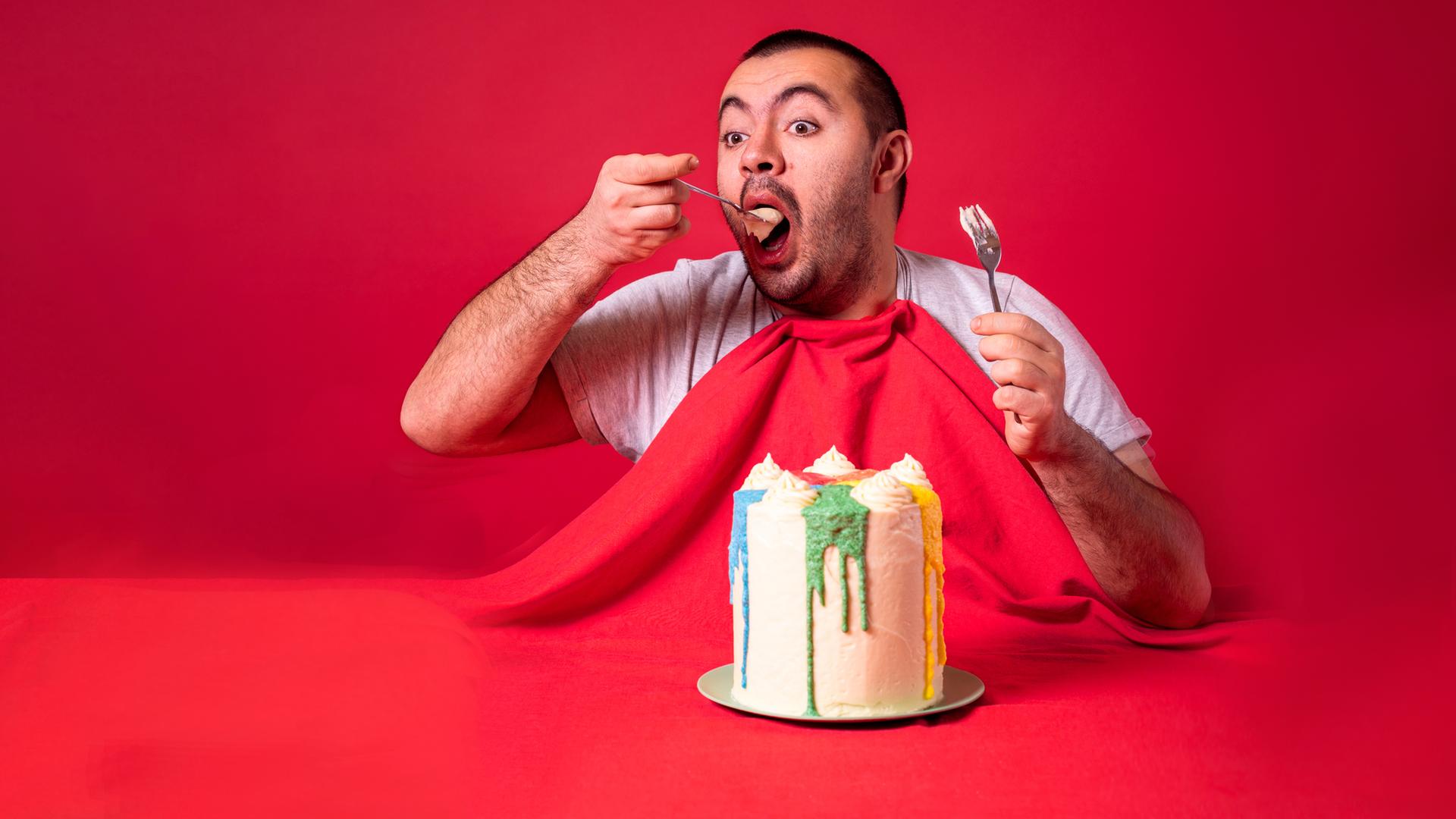 Mann isst allein Geburtstagskuchen. Gieriger Kerl isst einen riesigen Kuchen.