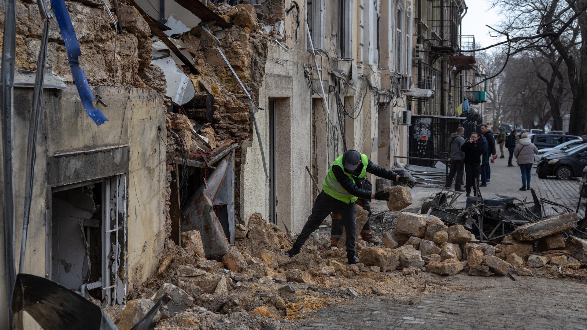 Ein städtischer Arbeiter räumt die Trümmer eines Wohnhauses auf.
