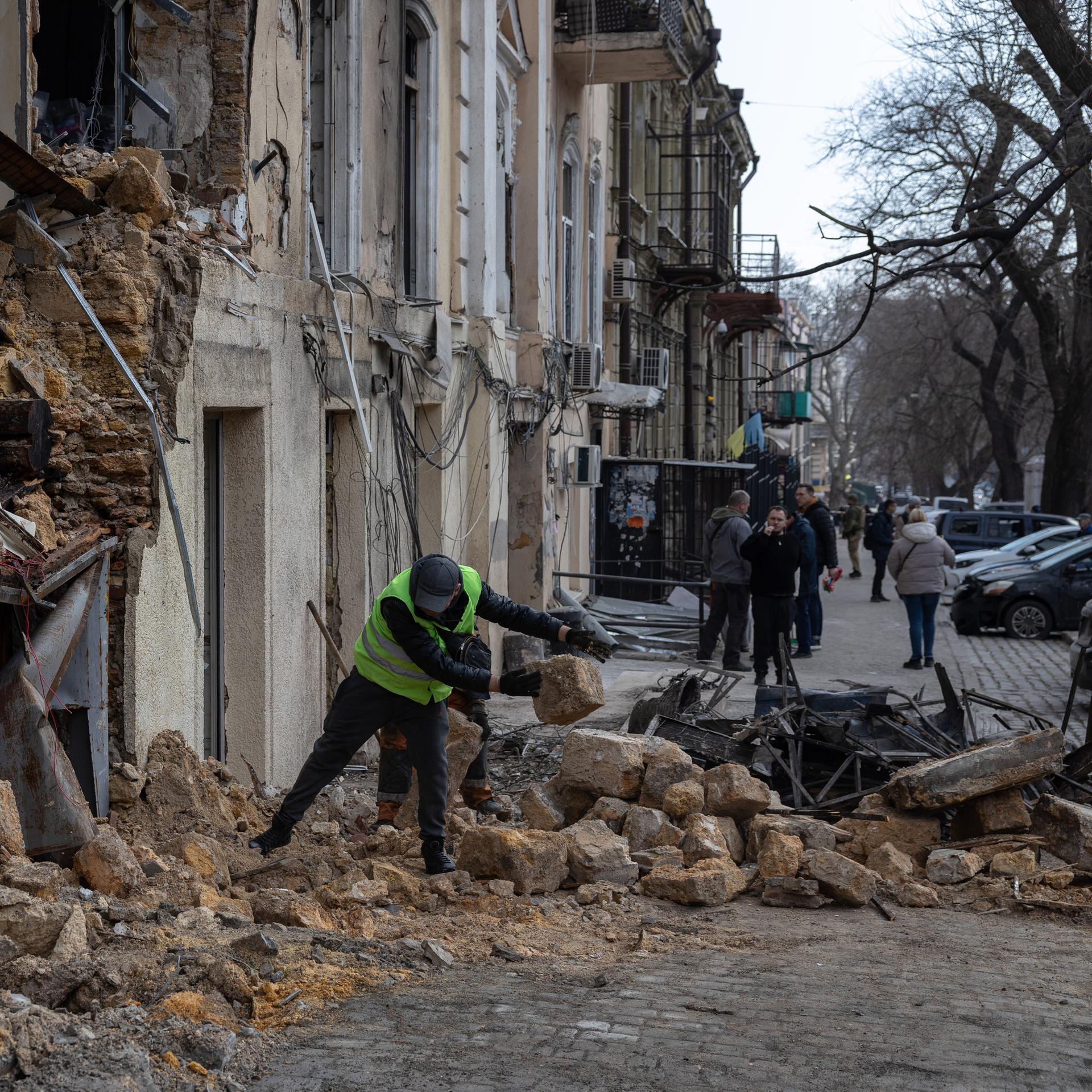 Ein städtischer Arbeiter räumt die Trümmer eines Wohnhauses auf.