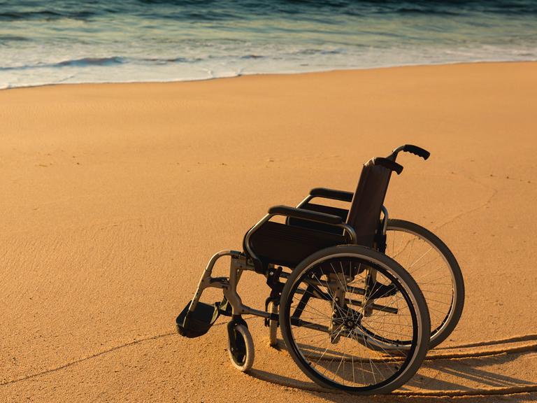 Verliert ein eingeschränktes Leben seinen Wert?  Zu sehen: Ein Rollstuhl an einem Sandstrand am Meer. 