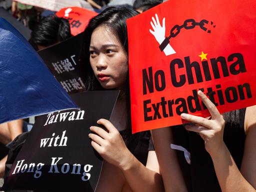 Eine junge Frau hält ein Plakat mit der Aufschrift "Taiwan with Hong Kong", eine andere eins mit "No China Extradition" bei einer Kundgebung in Taipeh, Taiwan, am 16.06.2019