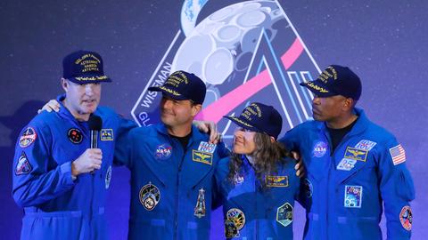 Die Besatzung der Artemis 2, drei Männer und eine Frau, steht auf einer Bühne, einer von ihnen hält ein Mikrofon in der Hand.