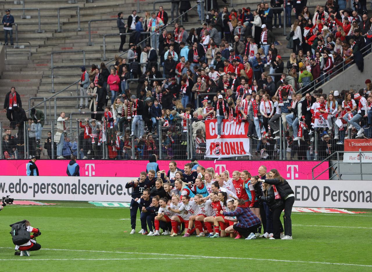Die Frauen des 1.FC Köln sammeln sich zum Mannschaftsfoto vor der gefüllten Kurve ihrer Fans. 