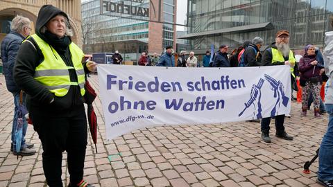 Demonstranten halten vor einem Kaufhaus ein Transparent mit der Aufschrift "Frieden schaffen ohne Waffen" hoch
