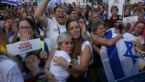 Menschen halten Israel-Flaggen in die Höhe und umarmen sich auf dem Platz der Geiseln in Tel Aviv, Israel (13.10.2025)