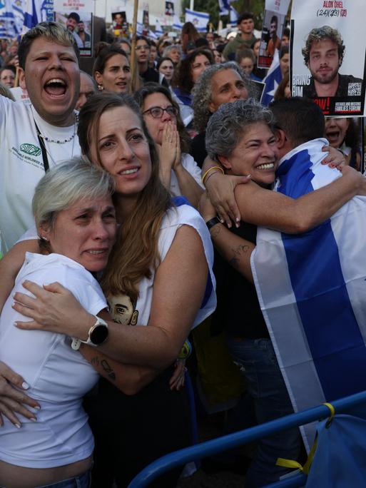 Menschen halten Israel-Flaggen in die Höhe und umarmen sich auf dem Platz der Geiseln in Tel Aviv, Israel (13.10.2025)