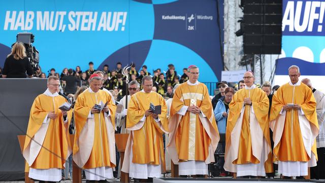 Der Vorsitzende der Deutschen Bischofskonferenz, Wilmer, und andere Geistliche stehen beim Abschlussgottesdienst auf einer Bühne. 
