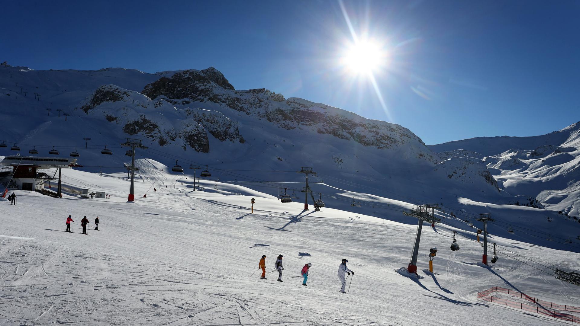 Wintersportler fahren im Skigebiet Ischgl im Sonnenschein.