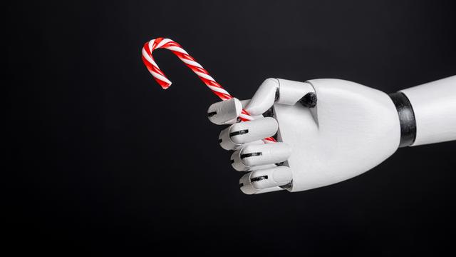 Eine Roboterhand hält Zuckerstange vor schwarzem Hintergrund. 