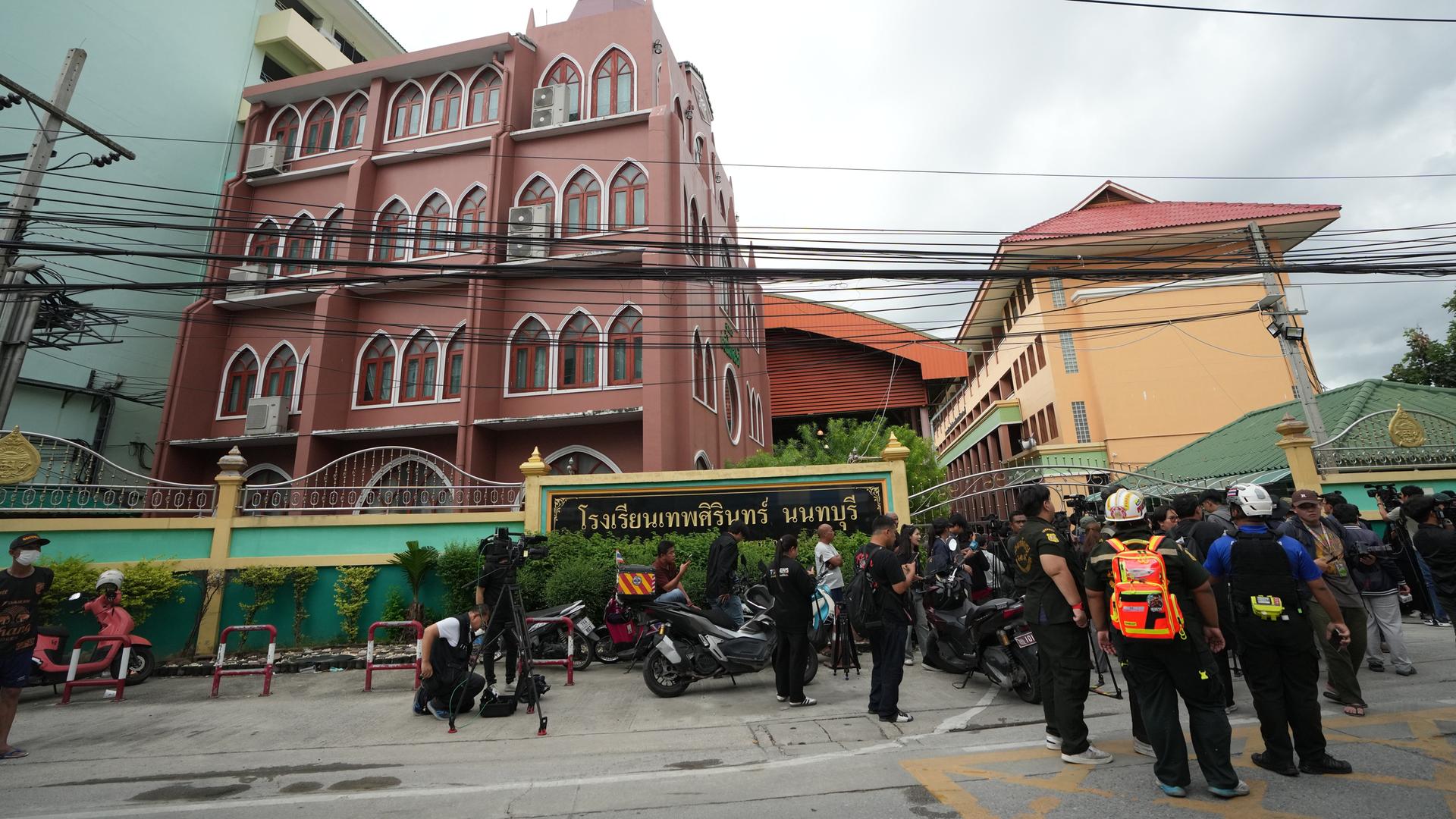 Menschen stehen nach dem Schussvorfall an der Debsirin Nonthaburi School in Thailand vor der Schule.