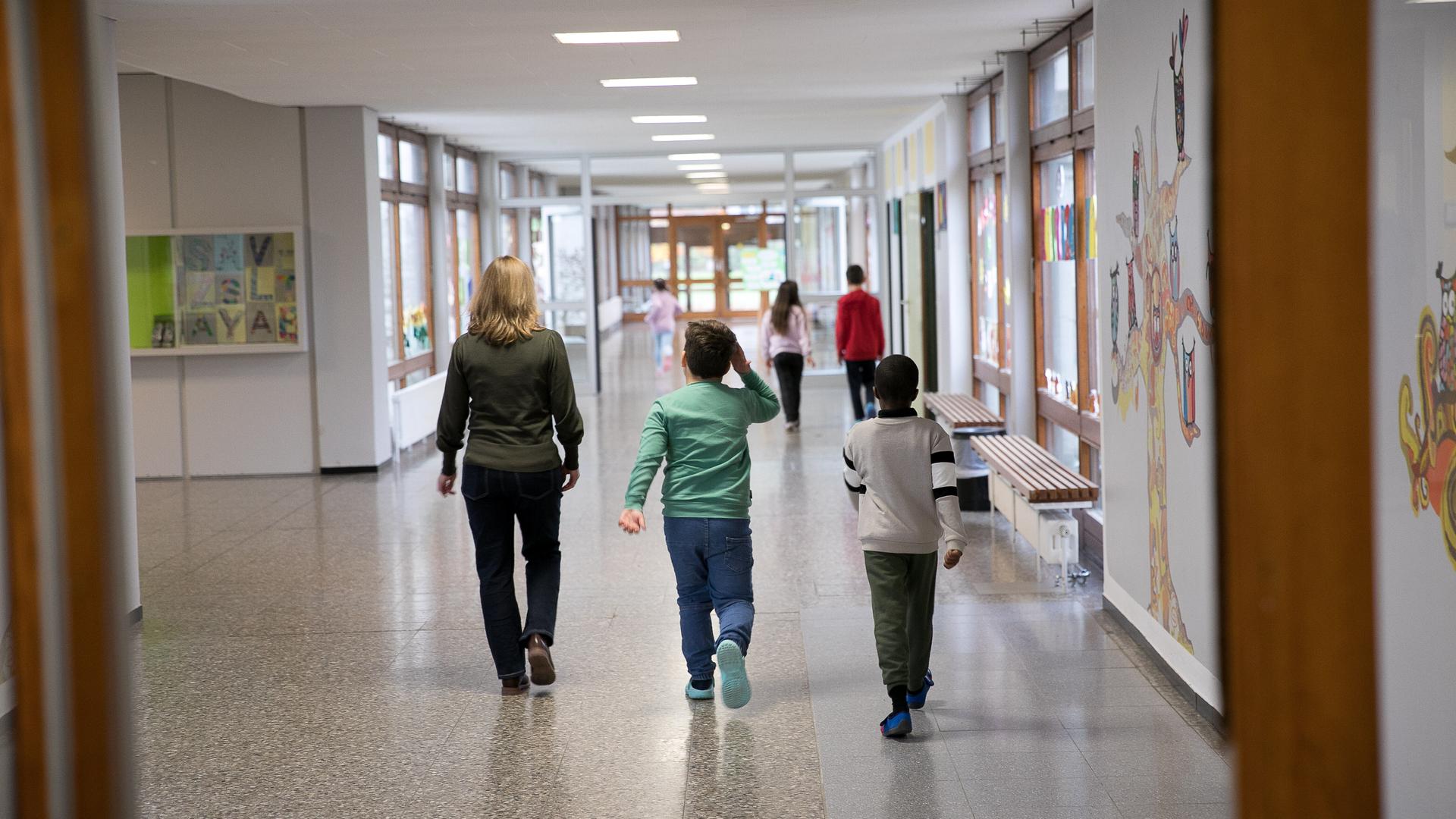 Schulkinder laufen mit einer Lehrerin einen Flur entlang
Schulkinder laufen mit einer Lehrerin einen Flur entlang