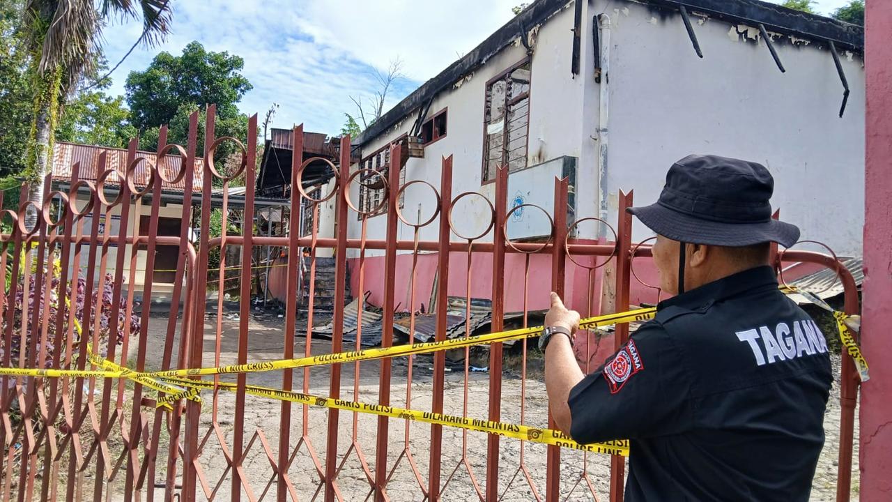 Ein Wachmann steht vor dem Tor eines Pflegeheims, das von einem Brand in Manado, Provinz Nordsulawesi, betroffen wurde. 