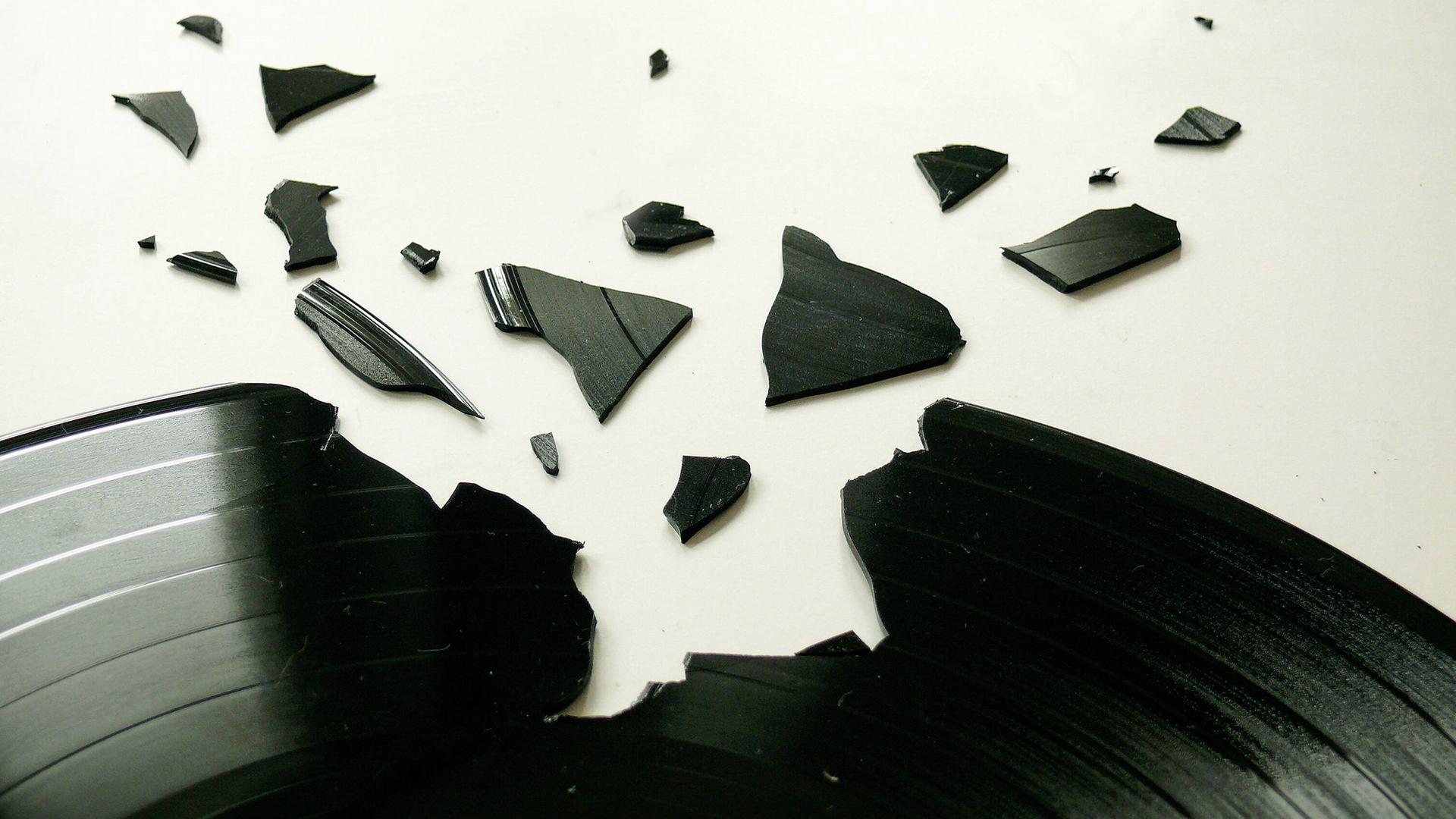 Eine schwarze Platte ist an einer Stelle zerbrochen. Die Bruckstücke liegen drumherum.
