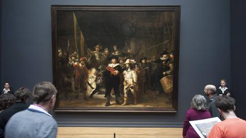 Besucher stehen im Rijksmuseum Amsterdam vor dem von zwei Museumswächtern bewachten Gemälde "Die Nachtwache" von Rembrandt  
