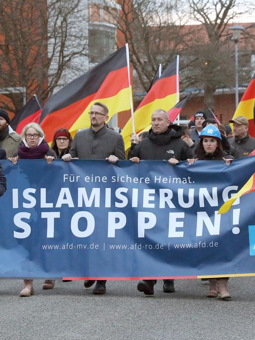 Menschen mit Deutschlandflaggen und einem Transparent mit dem Schriftzug "Islamisierung stoppen!": AfD-Demonstration 2019 gegen den Bau einer Moschee in Rostock.