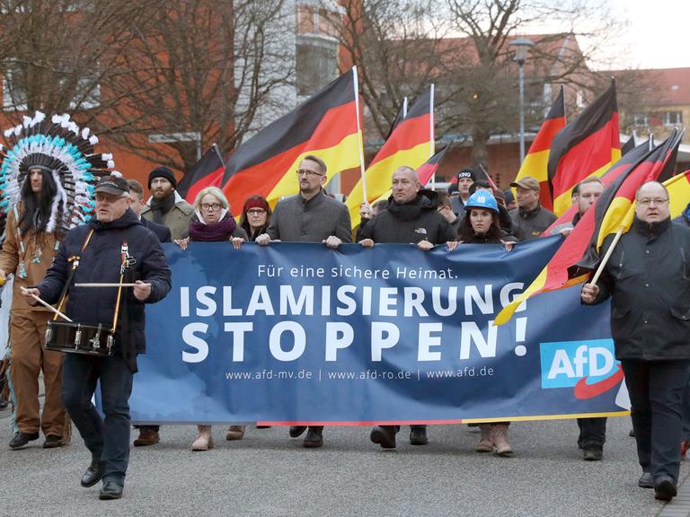 Menschen mit Deutschlandflaggen und einem Transparent mit dem Schriftzug "Islamisierung stoppen!": AfD-Demonstration 2019 gegen den Bau einer Moschee in Rostock.