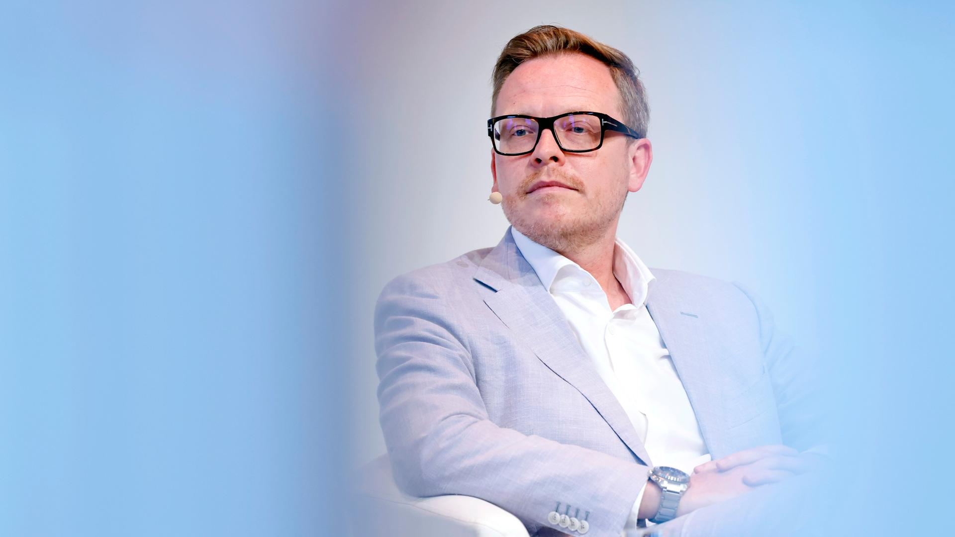 Porträt des Philosophen Markus Gabriel in einer Phil.Cologne Veranstaltung. Um ihn herum ist der Vordergrund hellblau verschwommen. Er trägt einen hellblauen Anzug und eine schwarze Brille. Porträt des Philosophen Markus Gabriel in einer Phil.Cologne Veranstaltung. Um ihn herum ist der Vordergrund hellblau verschwommen. Er trägt einen hellblauen Anzug und eine schwarze Brille.