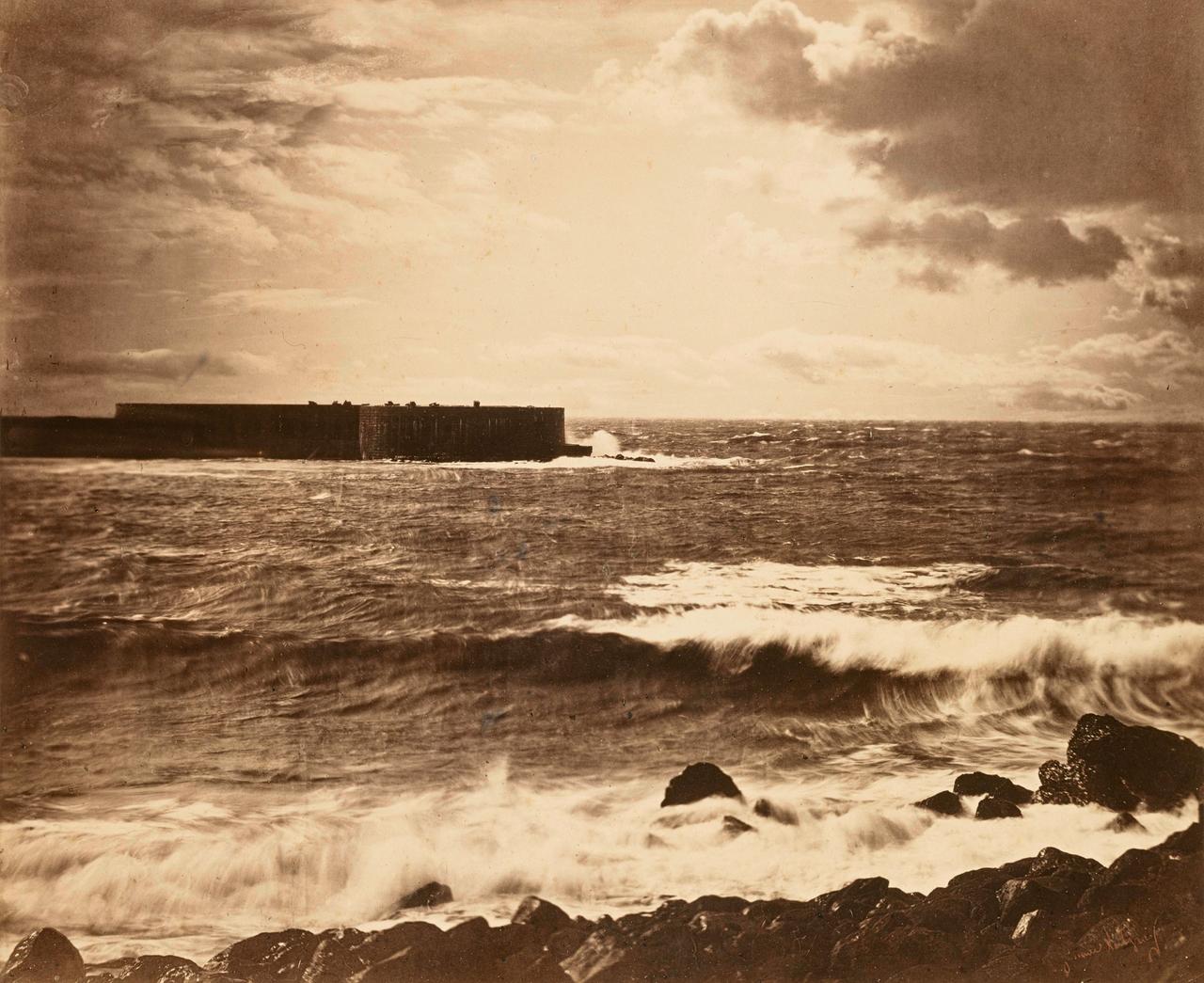 Eine frühe Fotografie des Meers, im Hintergrund wird eine Festung vom Wasser umspült.