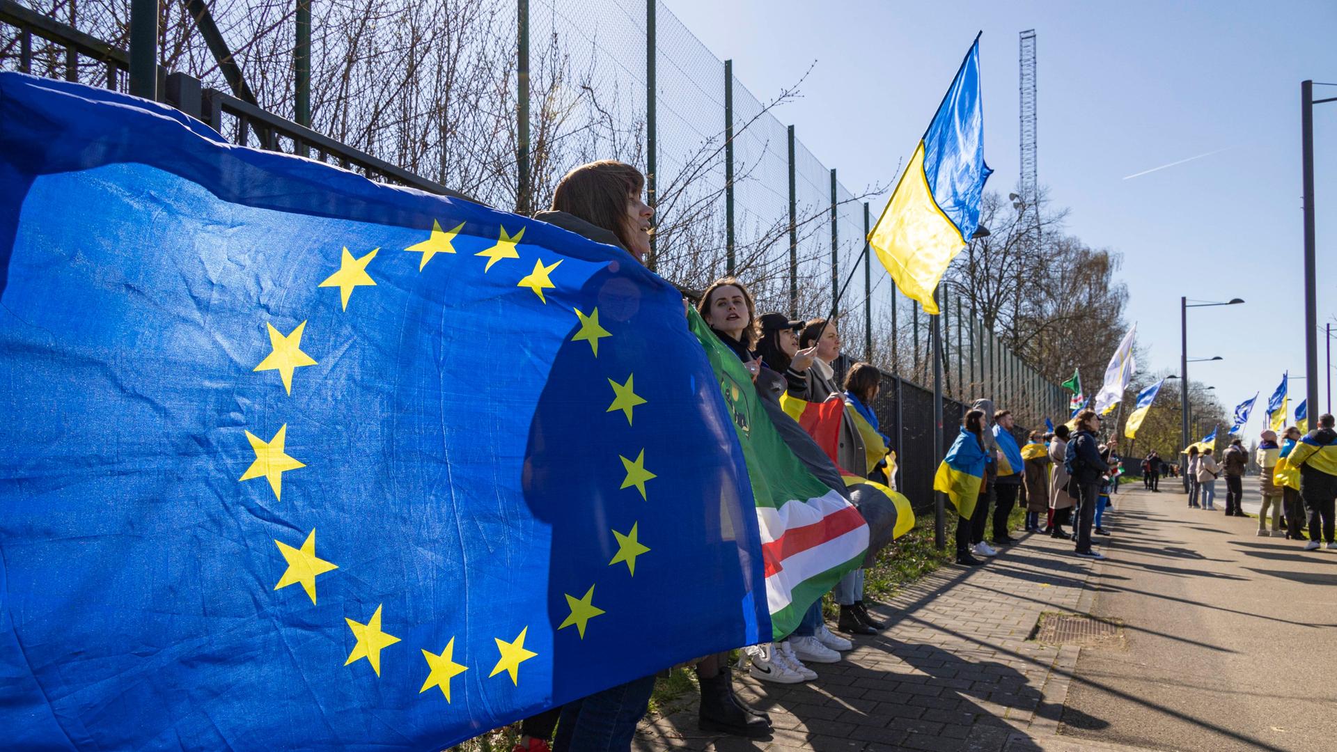 Eine EU-Fahne und viele blau-gelbe Fahnen der Ukraine sind auf einer Demonstration in Brüssel zu sehen.