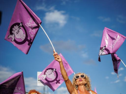 Eine Frau schwenkt auf einer Demonstration gegen den ehemaligen spanischen Fußballfunktionär Rubiales am 1. September 2023 in Madrid eine rosafarbene Fahne mit dem Symbol der Frauenbewegung. Eine Frau schwenkt auf einer Demonstration gegen den ehemaligen spanischen Fußballfunktionär Rubiales am 1. September 2023 in Madrid eine rosafarbene Fahne mit dem Symbol der Frauenbewegung.