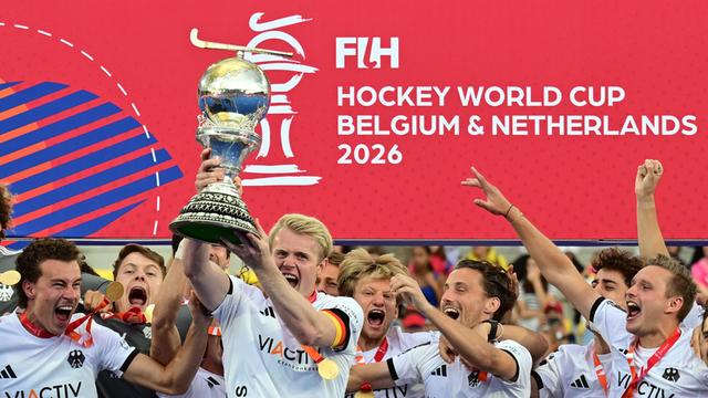 Die deutsche Hockey-National-Mannschaft feiert auf dem Podium mit dem Pokal den Sieg.