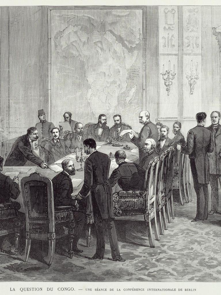 Eine Zeichnung aus 1884 zeigt die Kongokonferenz in Berlin; an einem Tisch sitzen Männer in Frack, weitere Männer stehen im Raum.