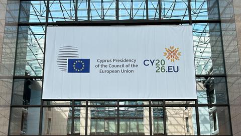 An einer Fensterfront hängt ein Plakat mit der EU-Flagge und einem Hinweis auf die zyprische Ratspräsidentschaft.