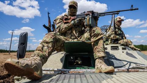 Russische Soldaten sitzen auf einem Panzer