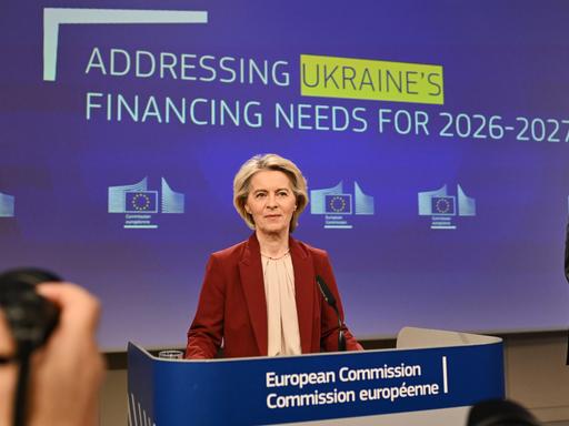 EU-Kommissionspräsidentin von der Leyen steht hinter einem Rednerpult. Hinter ihr auf der Leinwand ist "Adressing Ukraine's Financing Needs for 2026-2027" zu lesen. EU-Kommissionspräsidentin von der Leyen steht hinter einem Rednerpult. Hinter ihr auf der Leinwand ist "Adressing Ukraine's Financing Needs for 2026-2027" zu lesen.